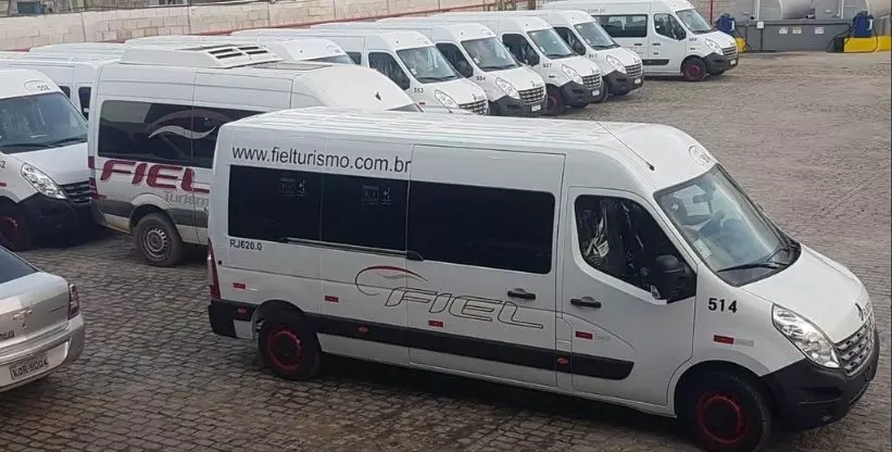 A foto mostra a frota de vans da empresa Fiel Turismo