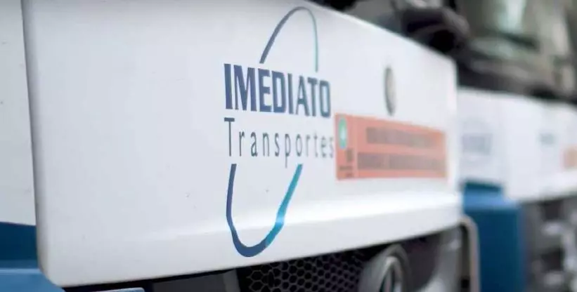 A imagem mostra o logotipo do Grupo Imediato, colado na grade do caminhão