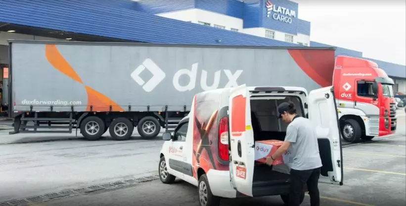 A foto mostra uma carreta, 1 fiorino e 1 entregador da empresa DUX Logístics