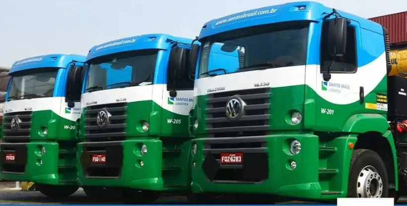 A foto mostra 3 caminhões da empresa Santos Brasil
