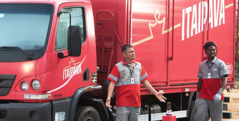 A foto mostra um caminhão da Cervejaria Petrópolis com a logomarca da Itaipava e dois entregadores do lado de fora.