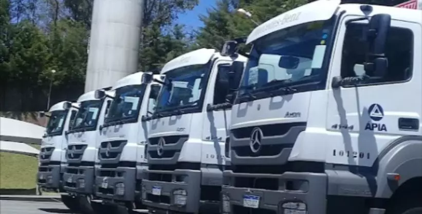 A foto mostra cinco caminhões basculantes da Construtora Àpia