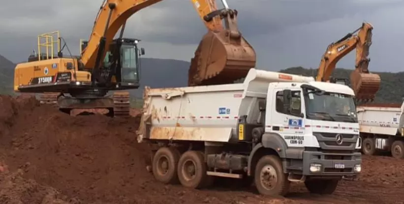 A foto mostra uma escavadeira carregando um caminhão da Salum Construções