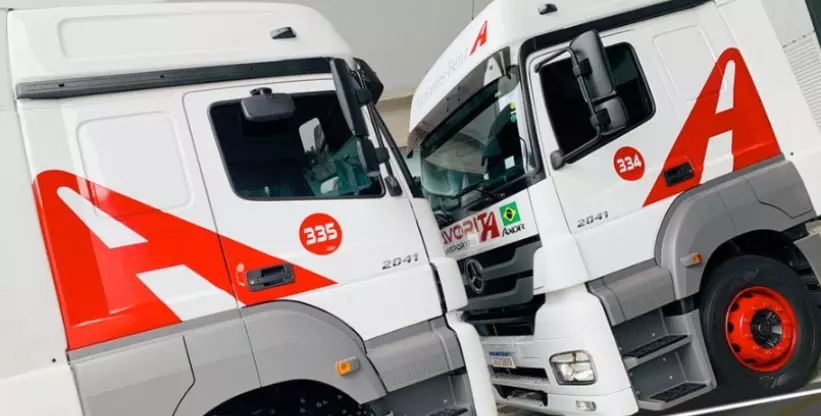 A foto mostra dois caminhões da empresa Favorita Transportes