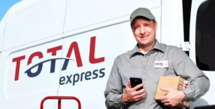 A foto mostra um motorista da Total Express fazendo entrega