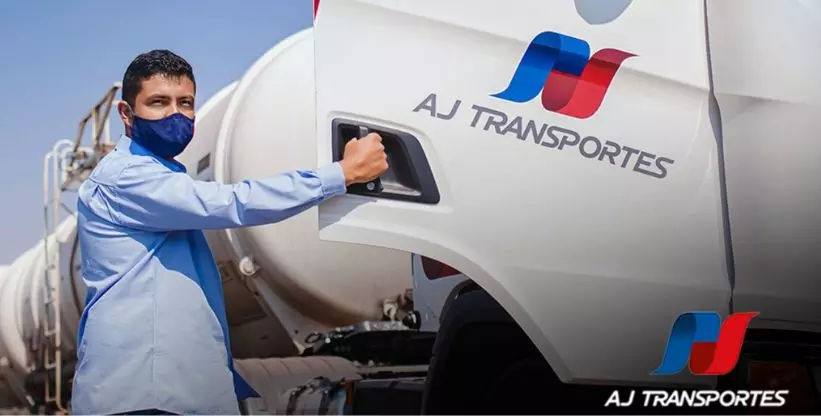 A foto mostra um funcionário da AJ Transportes abrindo a porta e entrando na carreta