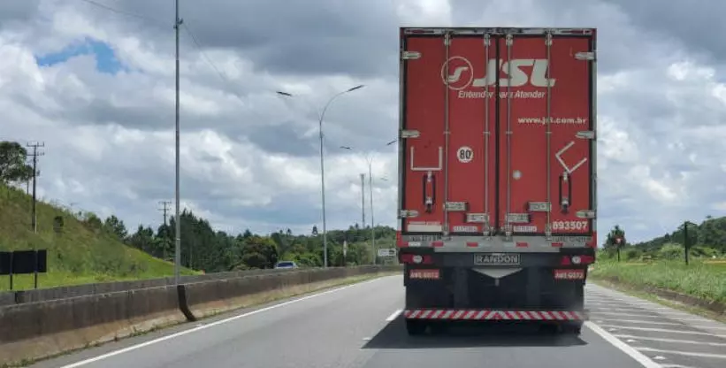 A foto mostra um caminhão da JSL na rodovia