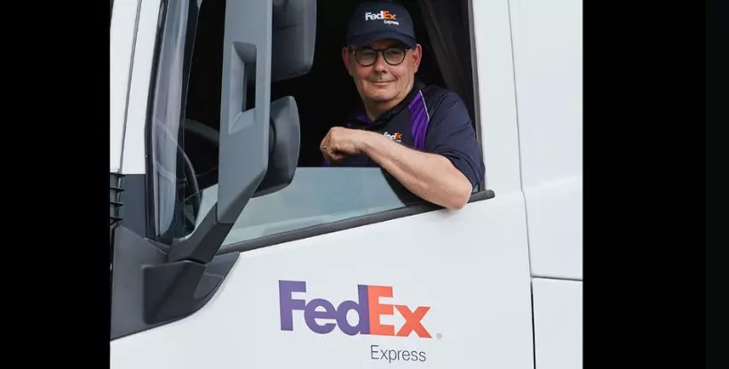 A foto mostra um motorista da FedEx dentro de um caminhão