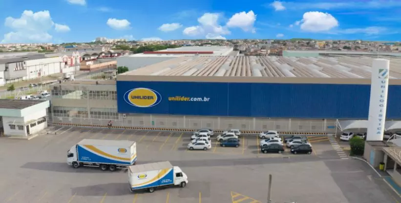 A foto mostra o galpão da empresa e veículos da frota da Unilider Distribuidora