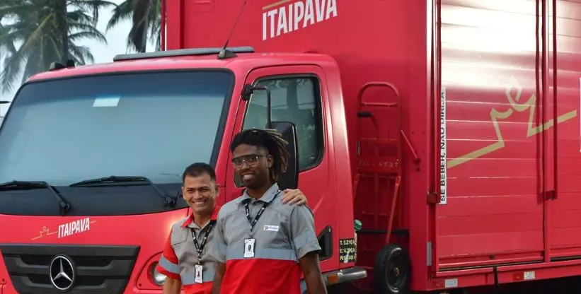 A foto mostra um caminhão da Cervejaria Petrópolis e dois motoristas