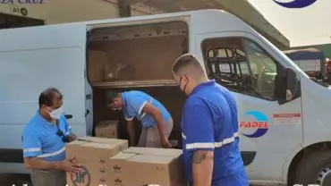 A foto mostra uma van da Fadel Transportes e 3 funcionários da empresa