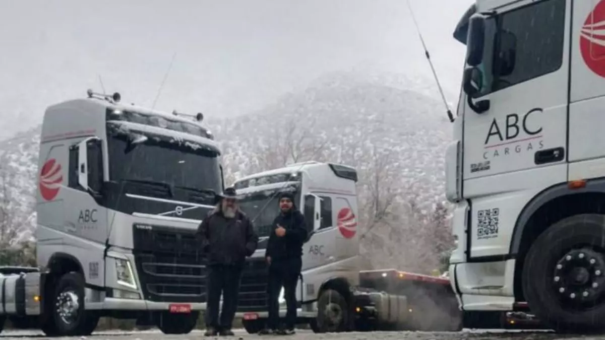 A foto mostra uma frota de caminhões e motoristas da ABC Cargas em um país com neve