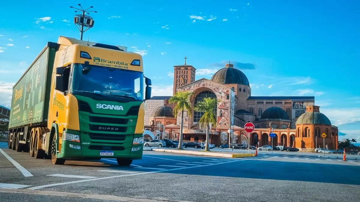A foto mostra uma carreta da Brambila Transportes e a Basílica de Nossa Senhora Aparecida